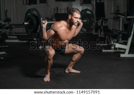 Handsome weightlifter lifting barbells with Squats. Male training with barbell, pumping legs