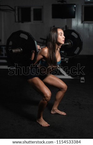 Handsome weightlifter lifting barbells with Squats. Female training with barbell, pumping legs