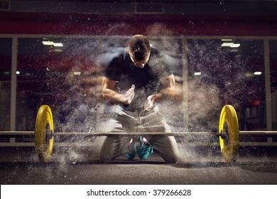 Handsome weightlifter preparing for training. Shallow depth of field, selective focus on hands and dust. - Powered by Shutterstock