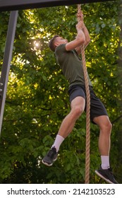 Handsome and well b uild guy is doing climbing the rope exercise