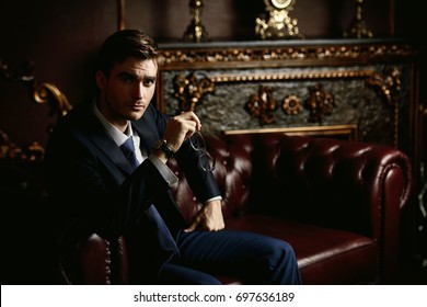 Handsome well-dressed young man in a room with classic interior. Business style. Luxury.