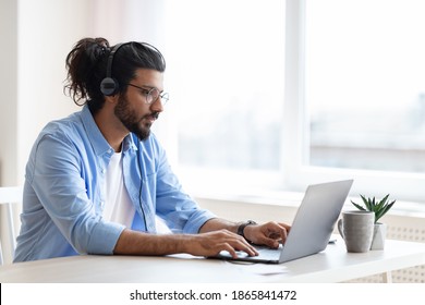 Handsome western freelancer guy working remotely with laptop at home office, using computer for online project or education, typing on keyboard, sitting at desk near window, copy space - Powered by Shutterstock