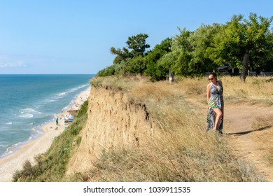 A handsome woman in a green dress is above the high seaside - Shutterstock ID 1039911535