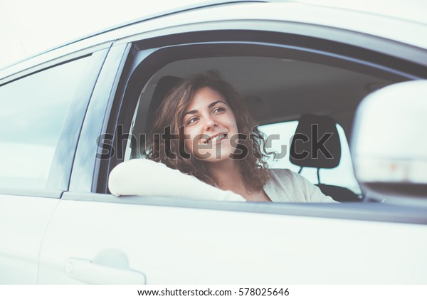 Handsome woman\
sitting in the car at sunny\
day