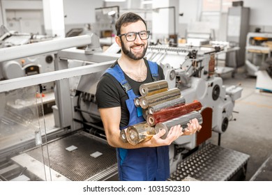 Handsome worker holding foil rolls for stamping standing at the vintage printing manufacturing - Shutterstock ID 1031502310