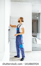 Handsome Workman Installing New Refrigerator In The Modern Kitchen At Home