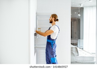 Handsome Workman Installing New Refrigerator In The Modern Kitchen At Home