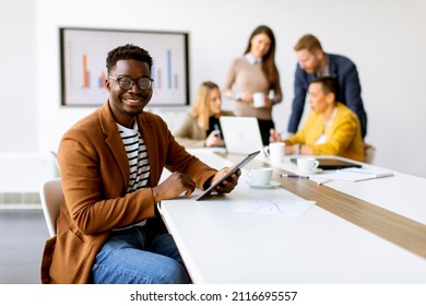Handsome young African American business man working with digital tablet in front of his coworkers at boardroom