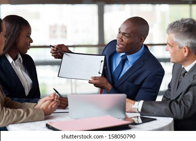 Handsome Young African American Businessman Presenting Figures At A Meeting With Team