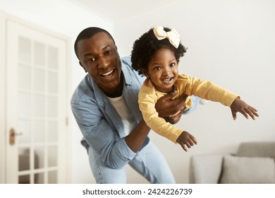 Handsome young african american father have fun with his daughter cute little girl at home. Happy black dad lifting up his beautiful toddler child, enjoying time together. Family, affectionate - Powered by Shutterstock