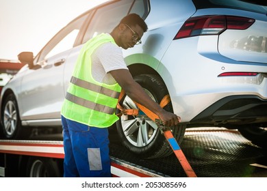 Handsome young African American man working in towing service on the road. Roadside assistance concept.