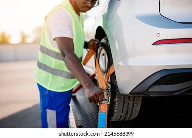 Handsome young African American man working in towing service on the road. Roadside assistance concept.