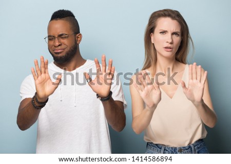 Handsome young african american man in eyeglasses and millennial caucasian woman denying, rejecting proposition, refusing bad deal offer, disagree with possible scam, diverse family couple saying no