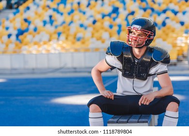 Handsome Young American Football Player Sitting On Bench At Sports Stadium