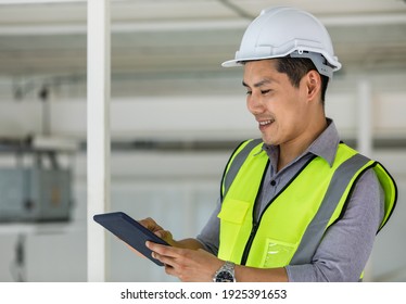 Handsome Young Asian Engineer In Yellow Reflective Vest And Wearing Safety Hardhat Working With Labtop Computer In Constrction Site.