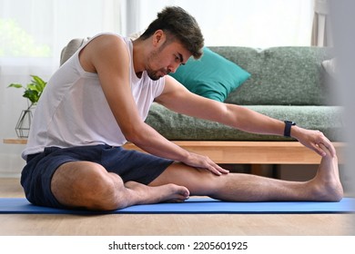 Handsome Young Asian Man Doing Hamstring Stretching Exercise At Home.