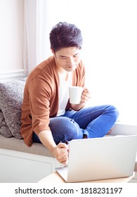 handsome young asian man drinking at home during COVID-19 - Shutterstock ID 1818231197