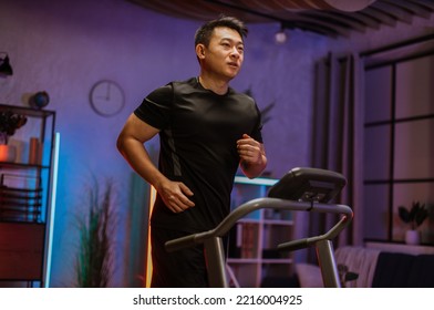 Handsome young asian man exercising, having workout on a treadmill in living room. Happy male running, having cardio training at evening, night time at home, healthy lifestyle concept. - Powered by Shutterstock