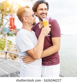 Handsome Young Attractive Male Couple, Gay Couple And Family, Valentine's Day At A Tropical Resort With Cocktails In Their Hands