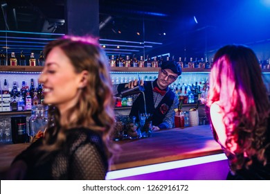 A handsome young bartender mixing a cocktail for a customer - Shutterstock ID 1262916172