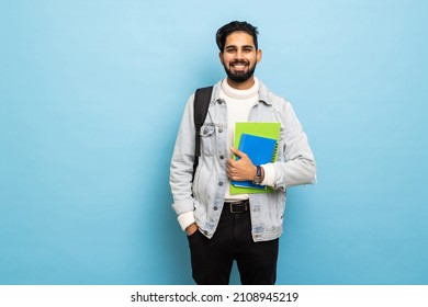 handsome young bearbed indian man with backpack hold books in studio background
