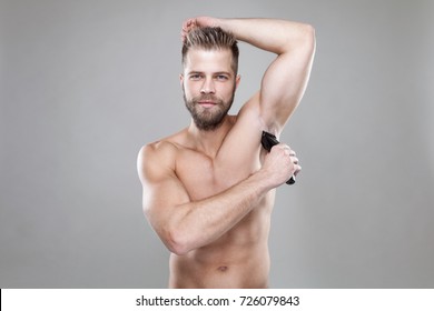 Handsome Young Bearded Man With A Trimmer Shaving Off Body Hair