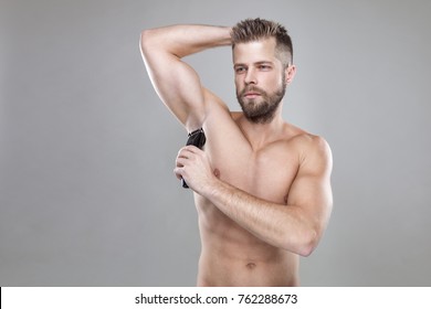 Handsome Young Bearded Man With A Trimmer Shaving Off Body Hair