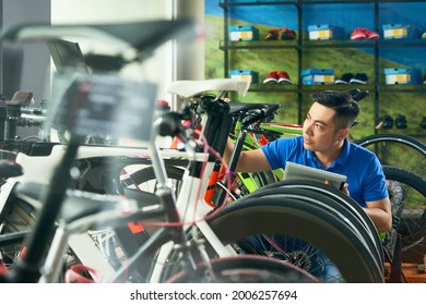 Handsome young bicycle store owner with digital tablet checking vehicles he received for selling - Powered by Shutterstock