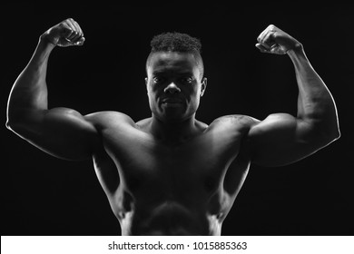 A Handsome Young Black Bodybuilder Flexing His Biceps. Double Biceps Pose. Front View. Monochrome Image.