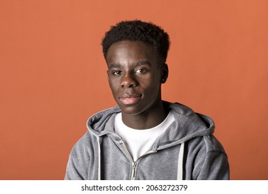 Handsome young Black man in a grey hoodie head and shoulders studio portrait as he looks thoughtfully at the camera with a quiet smile