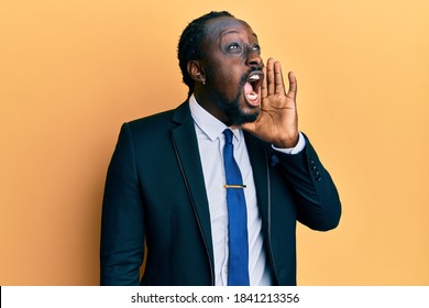 Handsome Young Black Man Wearing Business Suit And Tie Shouting And Screaming Loud To Side With Hand On Mouth. Communication Concept. 