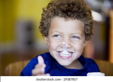 Handsome young boy with blue eyes eating yogurt