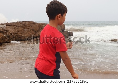 A handsome young boy enjoying his holidays in Morocco. A Cute boy wearing a red T-Shirt and looking at the sea waves. Moroccan atlantic coast.