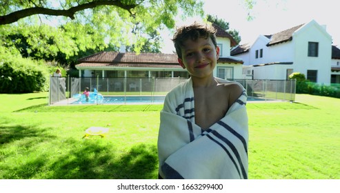 
Handsome young boy posing to camera after swimming pool wrapped in towel smiling