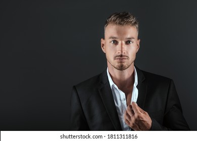 Handsome Young Brunette Model, Wearing In Black Suit, Looking With Attitude, Posing At Studio, Isolated On Black Background. Business Man Portrait. Copy Space.