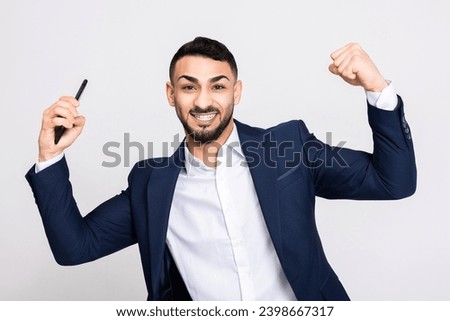 Handsome young buisnessman in ellegant smart suit costume over grey background in studio isolated celebrating the victory standing over grey background in studio isolated. Man trading gambling online. Stock photo © 