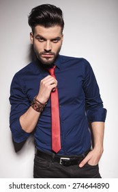 Handsome young business man pulling his tie while holding one hand in his pocket.