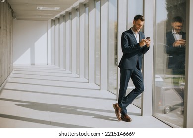 Handsome Young Business Man Using Mobile Phone In The Modern Office Hallway