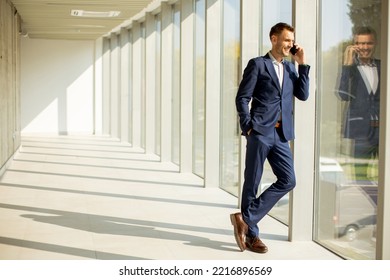 Handsome Young Business Man Using Mobile Phone In The Modern Office Hallway