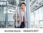 Handsome young businessman with clipboard entering the door in office