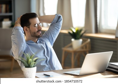 Handsome young businessman resting at workplace lean on comfort chair closed eyes enjoy fresh conditioned air. Satisfied employee finish work feels serene relaxing in modern office, no stress concept