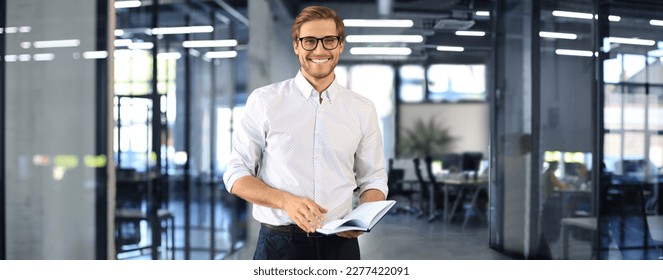 Handsome young businessman standing in modern office - Powered by Shutterstock