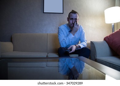 Handsome Young Caucasian Man In A Blue Shirt And Bow Tie Watching TV Crying