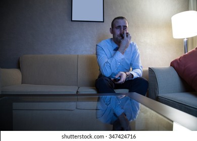 Handsome Young Caucasian Man In A Blue Shirt And Bow Tie Watching TV Crying