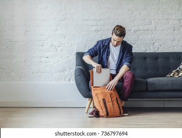 Handsome Young Caucasian  Man Packing Laptop In Backpack.