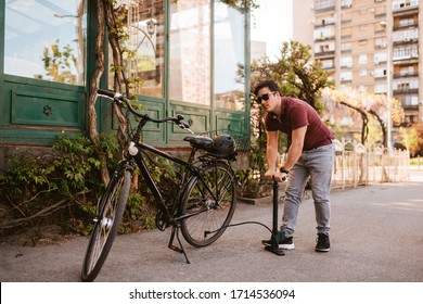 Handsome young caucasian man pumps a bicycle tire - Powered by Shutterstock