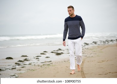 Handsome Young Caucasian Man Walking Alone With Bare Feet On The Beach