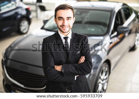 Handsome young classic car salesman standing at the dealership