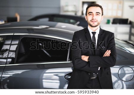 Handsome young classic car salesman standing at the dealership