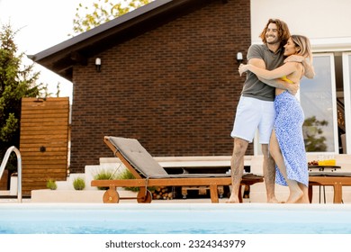 Handsome young couple relaxing by the swimming pool in the house backyard - Shutterstock ID 2324343979